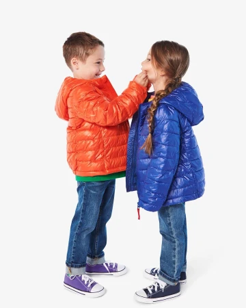 Young boy in an orange puffer jacket pinching the cheek of a young girl in a blue puffer jacket