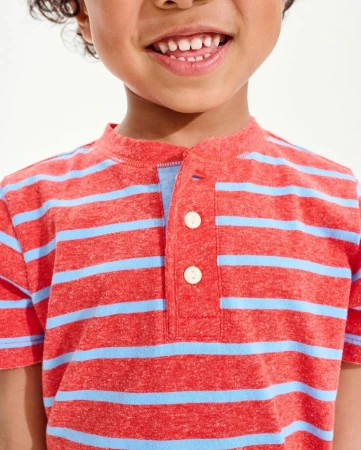 Close-up of a smiling child in a striped orange t-shirt, showcasing their upper body and joyful expression against a bright background.
