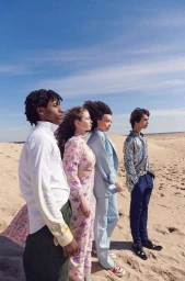 Four diverse models standing in a line on sandy dunes under a clear blue sky, photographed by Erin Foster in New York.
