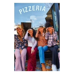 Four women sitting side by side holding pizza slices over their faces outside a pizzeria in New York captured by Erin Foster