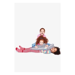 Three children playing together on a plain white studio background wearing striped clothing