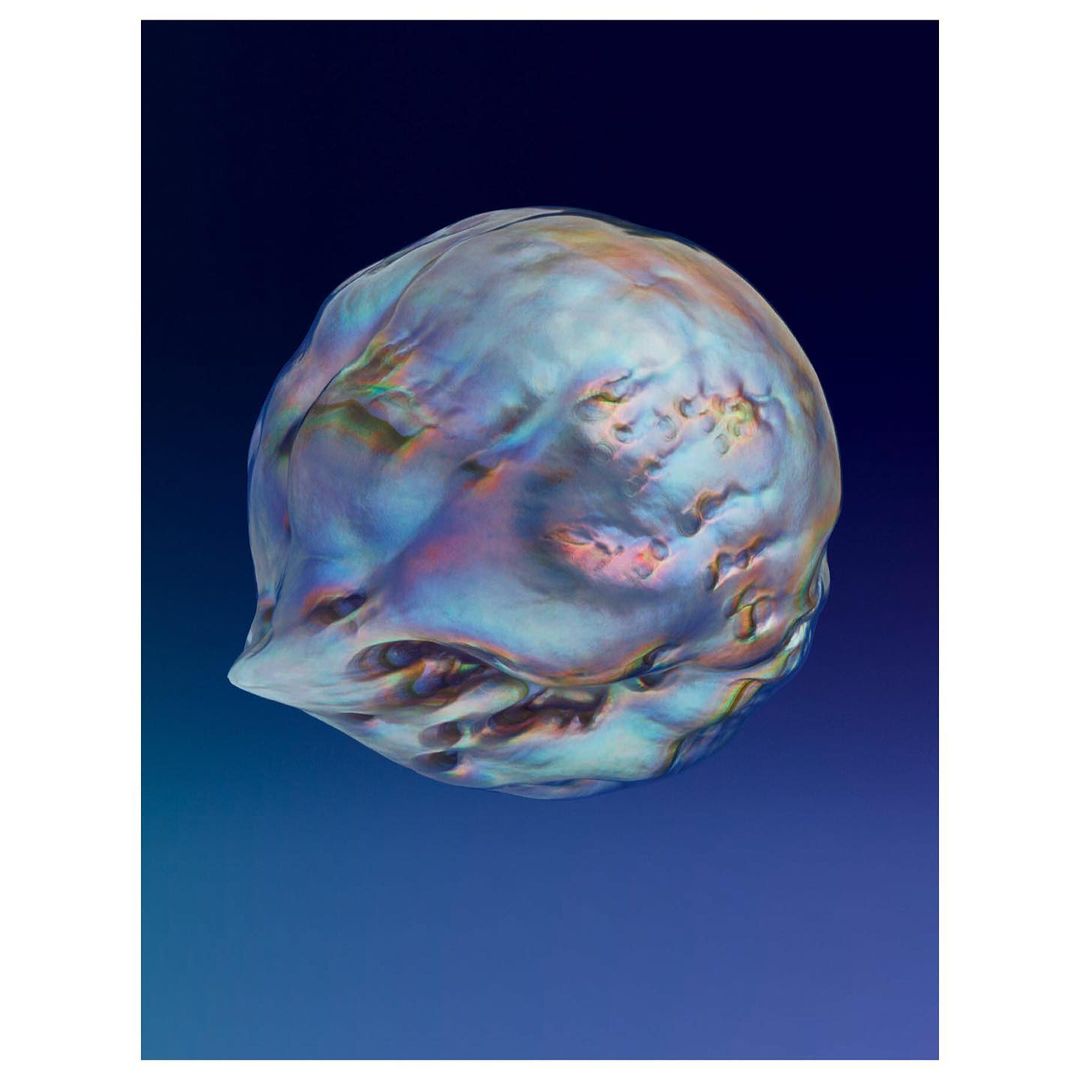 Iridescent sphere against a blue gradient backdrop. Smooth, textured surface catches the light with a range of shimmering colours and textures.