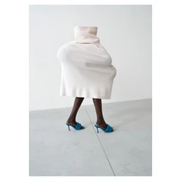 Surreal fashion portrait by Erwin Wurm featuring a person concealed beneath an oversized white sculptural garment wearing blue high heels