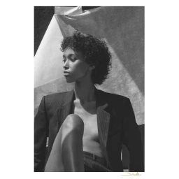Monochrome portrait of a woman with curly hair wearing a pinstripe blazer, photographed by Ester Grass Vergara.