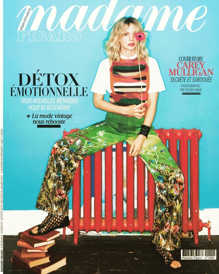 Magazine cover of Madame Figaro featuring Carey Mulligan in patterned clothing, holding a flower, sitting next to a red radiator.