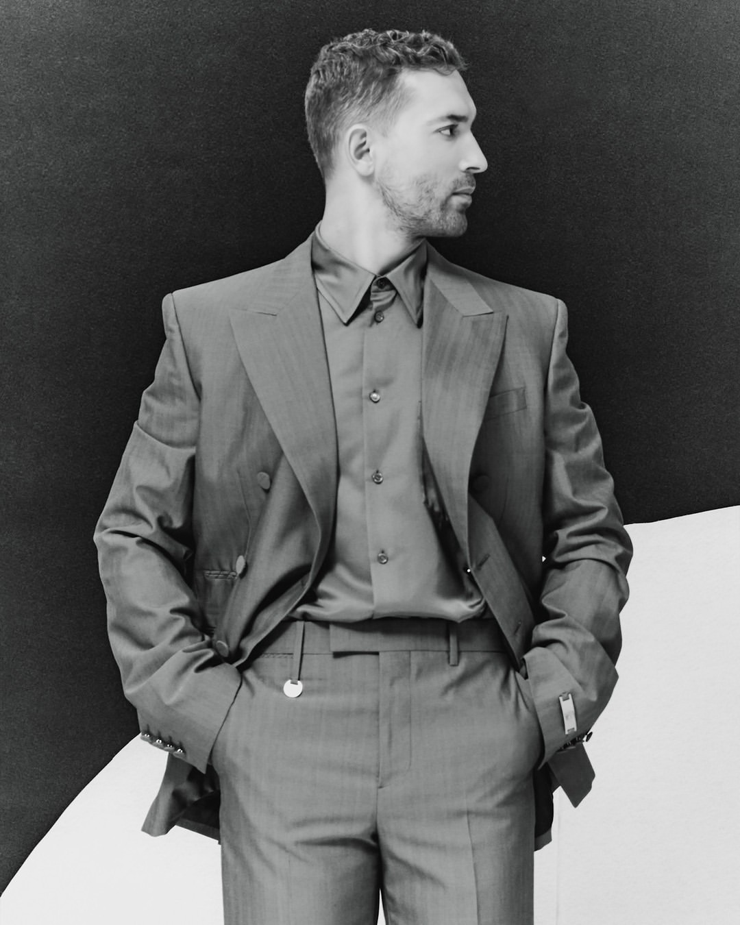 Black and white portrait of an adult male in a suit looking to the side, against a split black and white background.