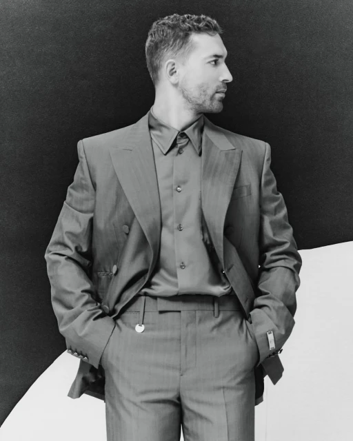Black and white portrait of an adult male in a suit looking to the side, against a split black and white background.