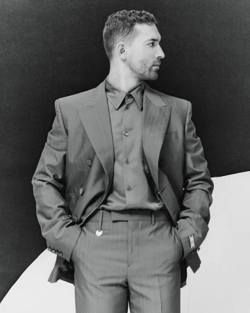 Black and white portrait of an adult male in a suit looking to the side, against a split black and white background.