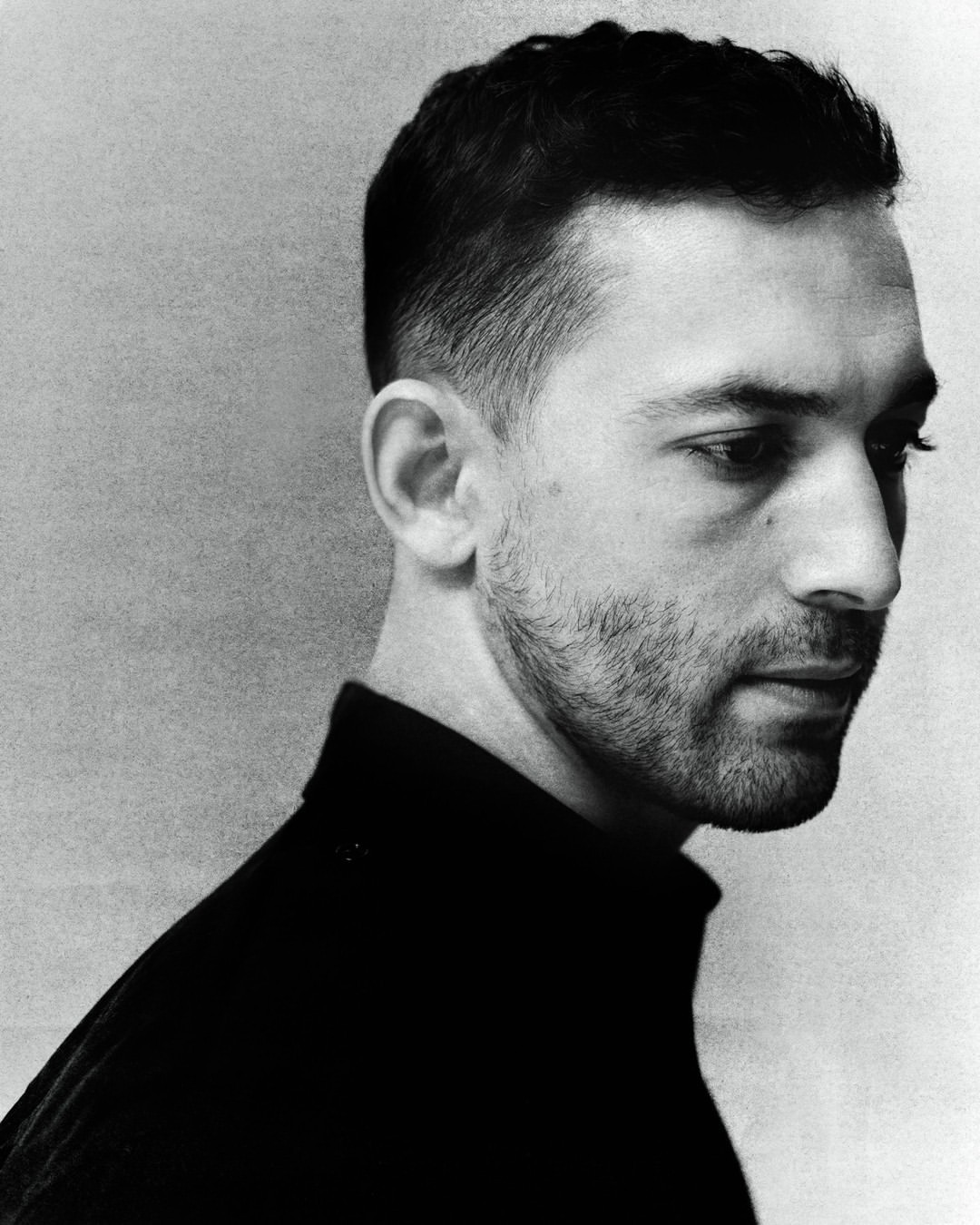 Monochrome portrait of a man in a black turtleneck looking away in profile by Ethan Hart in London