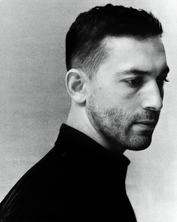 Monochrome portrait of a man in a black turtleneck looking away in profile by Ethan Hart in London