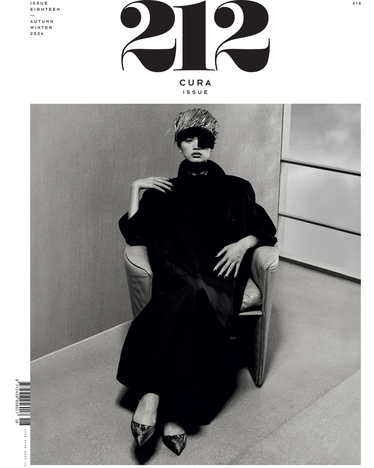 Black and white magazine cover featuring a woman in a chair, wearing a distinctive hat and coat, with the magazine's title at the top.