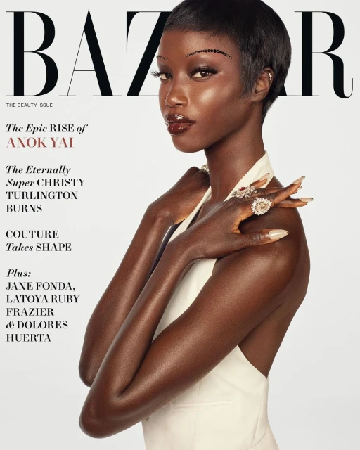 Fashion magazine cover featuring a close-up portrait of a dark-skinned woman with short hair, wearing jewelry and a light-colored top.
