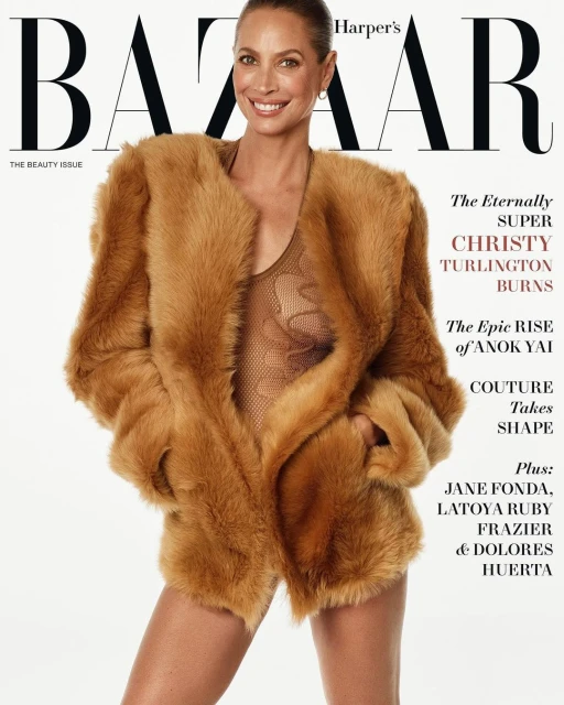 Christy Turlington Burns on the cover of Harper's Bazaar in a large fur coat, smiling against a clean white background.