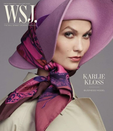 Magazine cover featuring Karlie Kloss in lilac hat and patterned scarf, wearing a trench coat, posing in a close-up indoor studio shot.