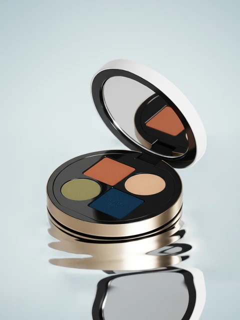 Eye shadow palette with multiple colors in round compact case with mirror. Beauty product in shades of green, brown, blue, and beige.