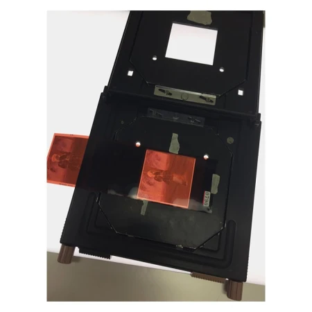 Film negative carrier holding film negatives against a white background. Film negatives are orange with visible silhouette of a person.