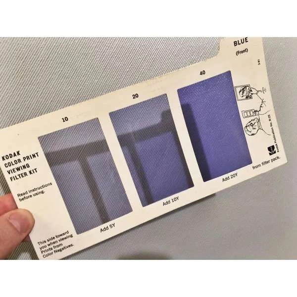 Kodak Color Print Viewing Filter Kit shows blue color samples on a white index card with a hand holding it, used in photography.