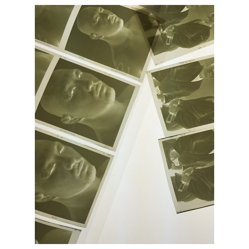 Collection of photographic prints featuring portrait of a human face, arranged against a white surface, exhibiting a vintage aesthetic.