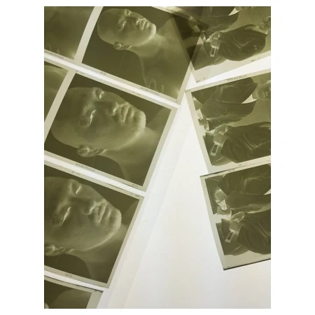 Collection of photographic prints featuring portrait of a human face, arranged against a white surface, exhibiting a vintage aesthetic.
