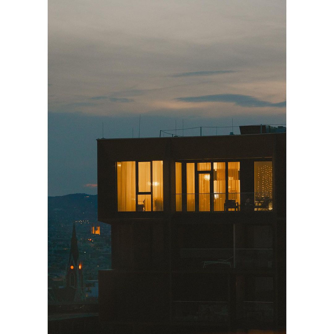 Exterior view of a modern building with illuminated windows during twilight, showcasing architectural design and urban living against a dusky sky.