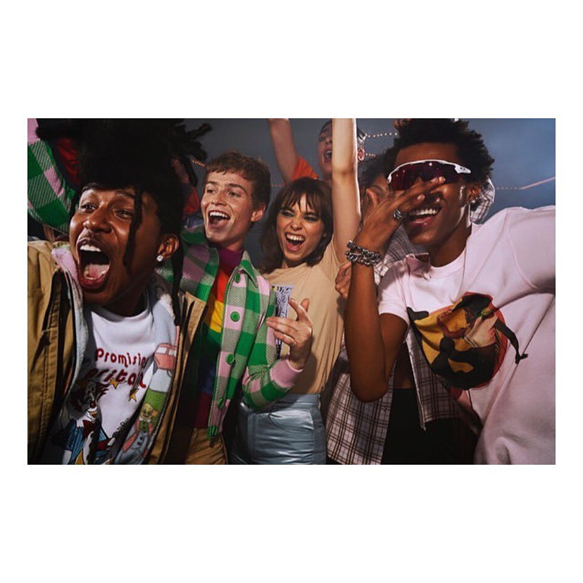 Enthusiastic group of young adults at a vibrant event, showcasing diverse fashion and joyful expressions, captured in a dynamic medium shot.