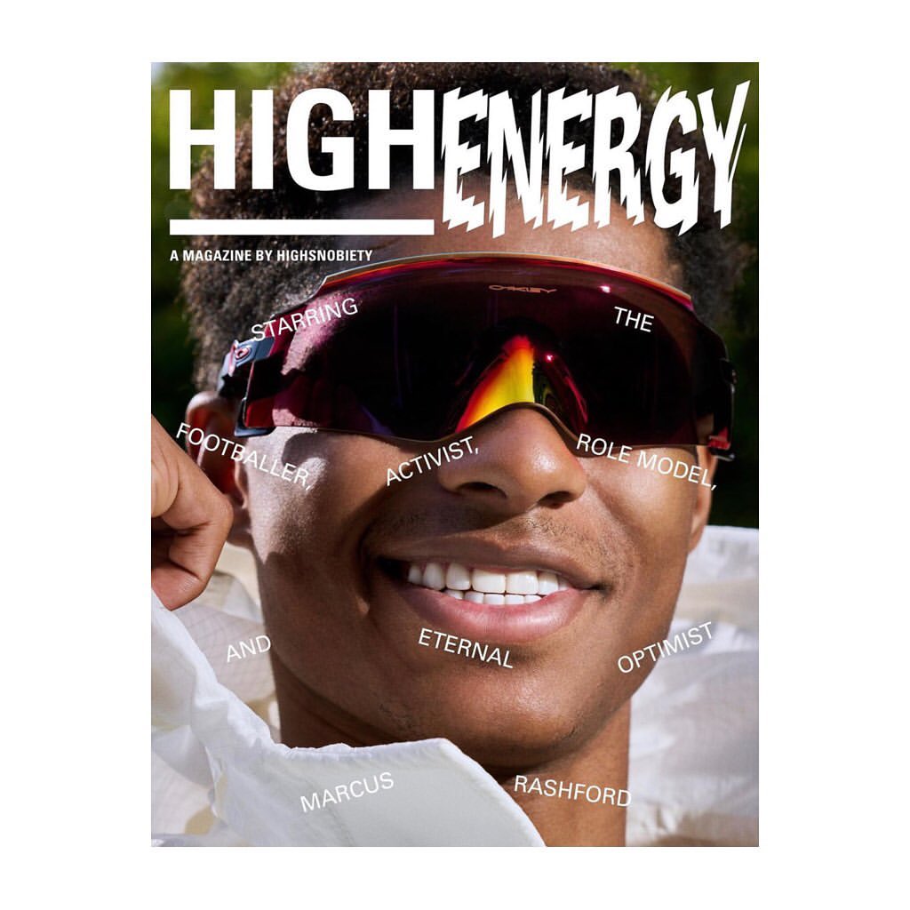 Close-up magazine cover featuring a smiling man with dark hair wearing reflective sunglasses against a blurred green background.