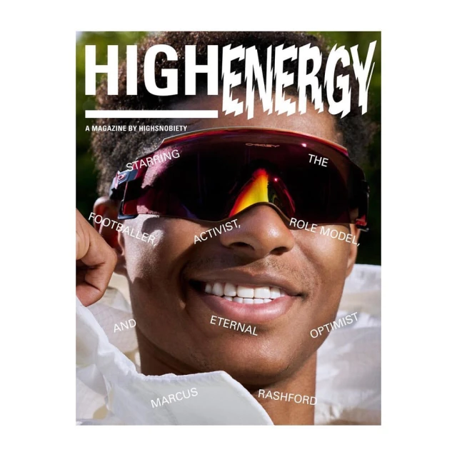 Close-up magazine cover featuring a smiling man with dark hair wearing reflective sunglasses against a blurred green background.