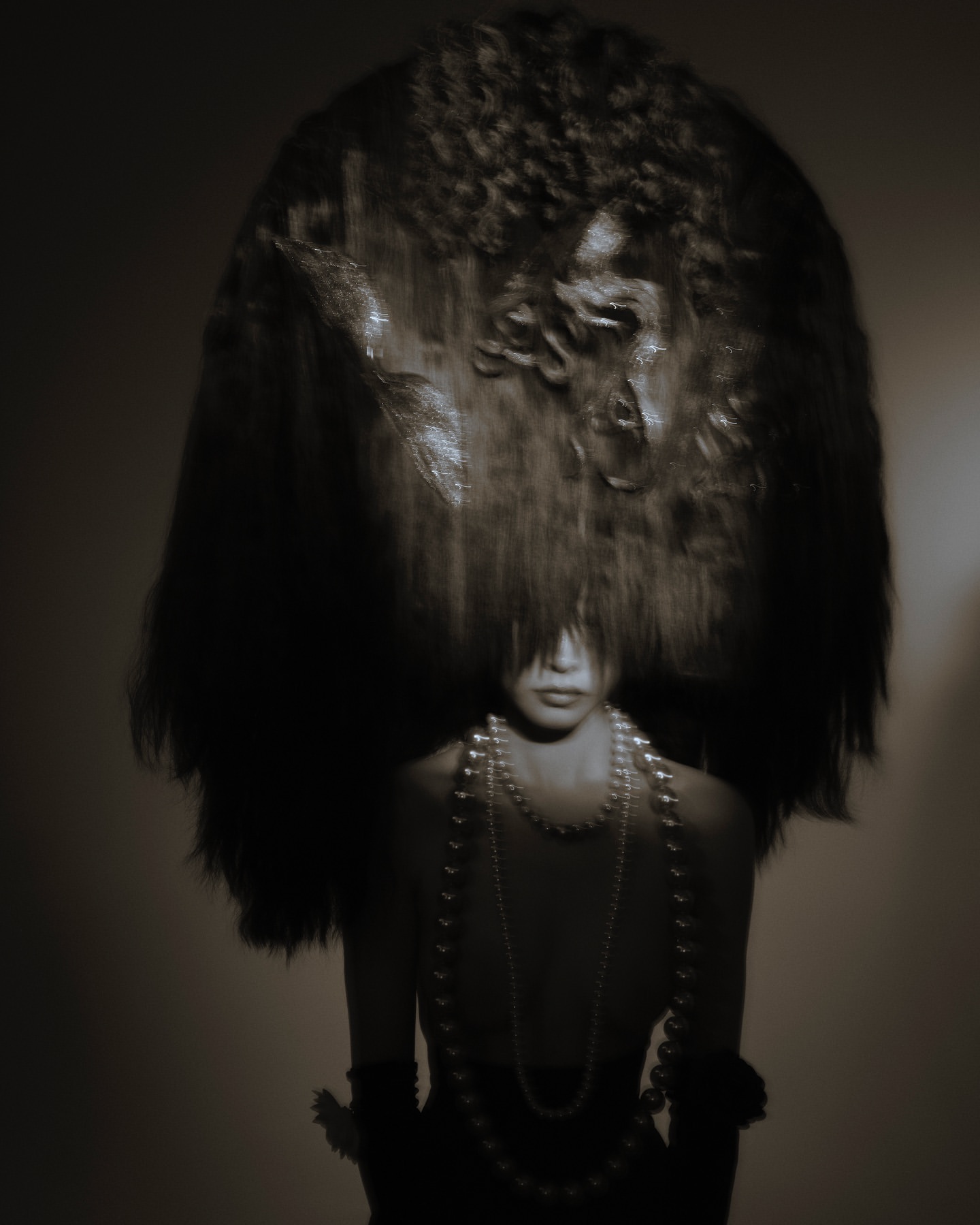 Portrait of a model wearing a large dark textured headdress and layered pearl necklaces photographed by Eylul Ezik