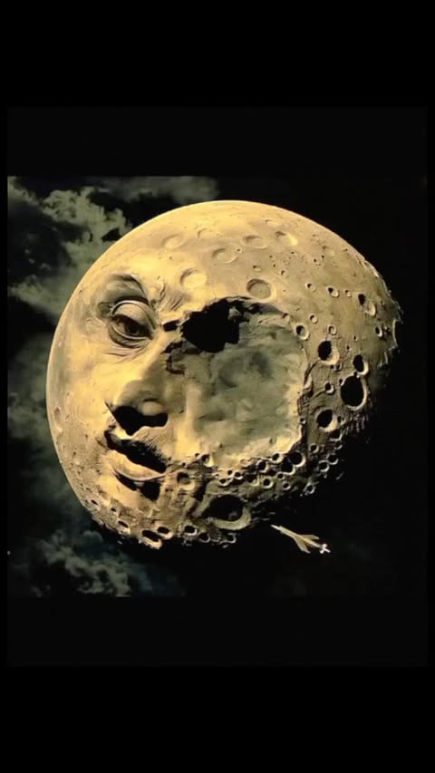Surreal image of a vintage moon with a human face, craters, and a star against a black background with cloud-like textures.
