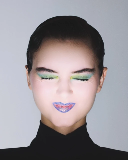 Close-up portrait of a woman with closed eyes, wearing vivid green eyeshadow and vibrant blue lipstick with reddish accents on her lips.