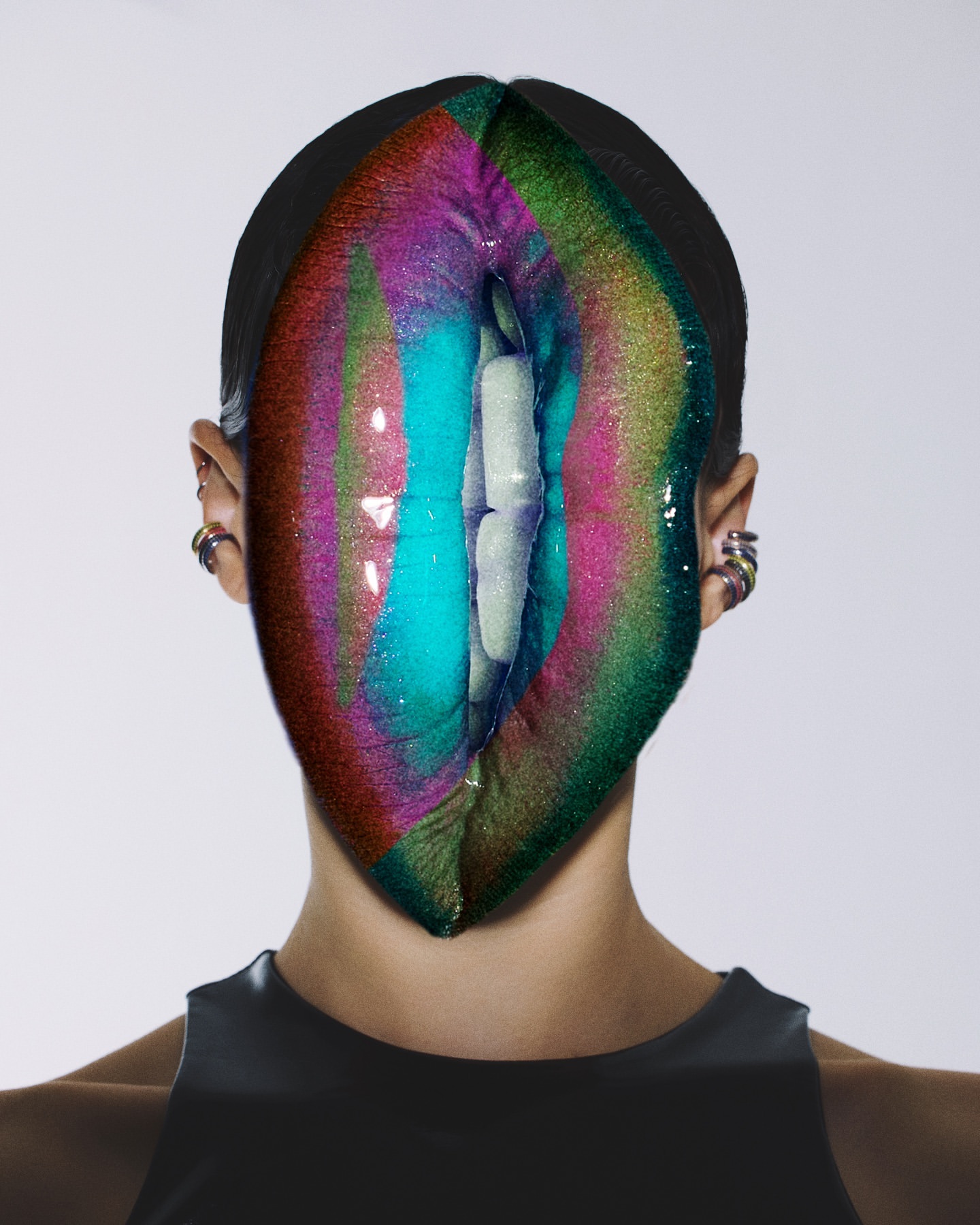 Woman with face makeup and jewelry stands in a bright studio. The makeup features colorful stripes with an open mouth as a design.