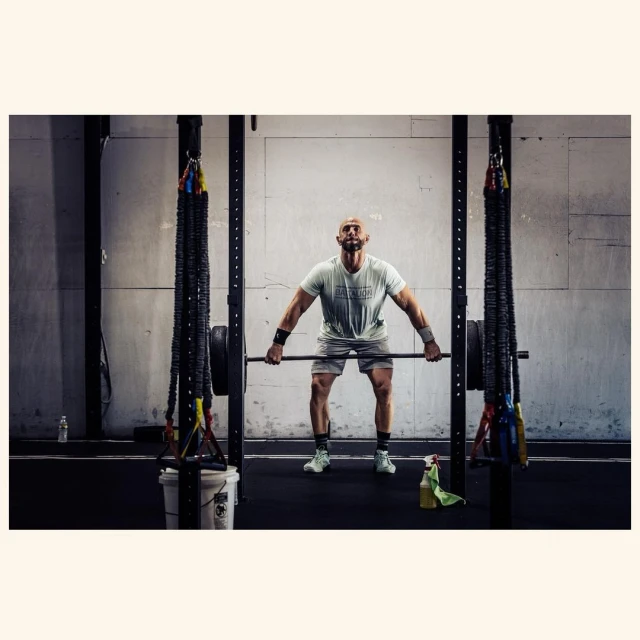 Athletic, muscular man lifts a barbell in a gym, dressed in sportswear with a determined expression. Strength and fitness training.