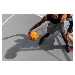 Basketball player dribbling a ball on an outdoor court, captured in a high-angle action shot by Fab Fernandez.