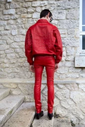 Man from behind wearing a vibrant red leather jacket and matching red leather trousers standing on stone steps.