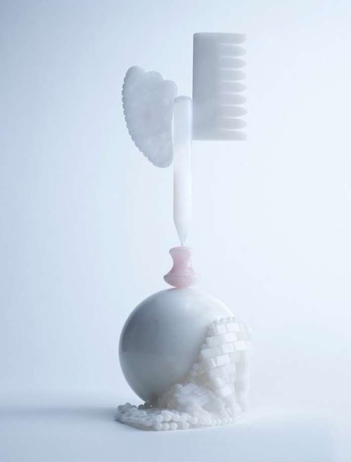 Stylized shot of white Gua Sha tool, comb, spherical object, and decorative beads against a soft, light background for beauty aesthetic.