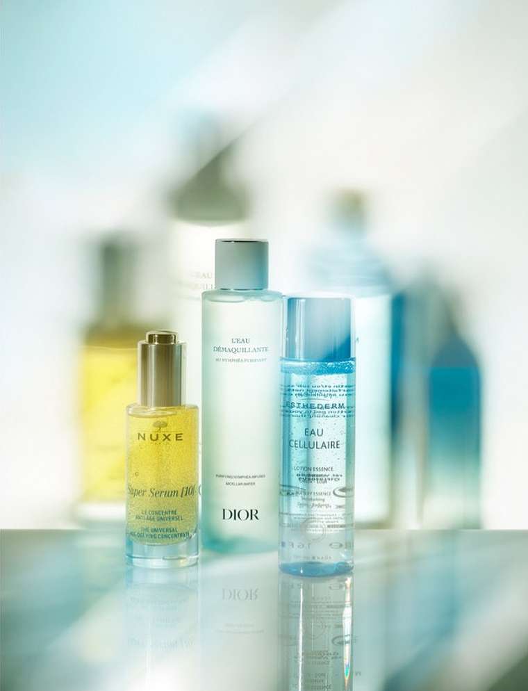 Several skincare products including serums and cleansers are arranged against a bright, diffused background, showcasing their packaging and textures.