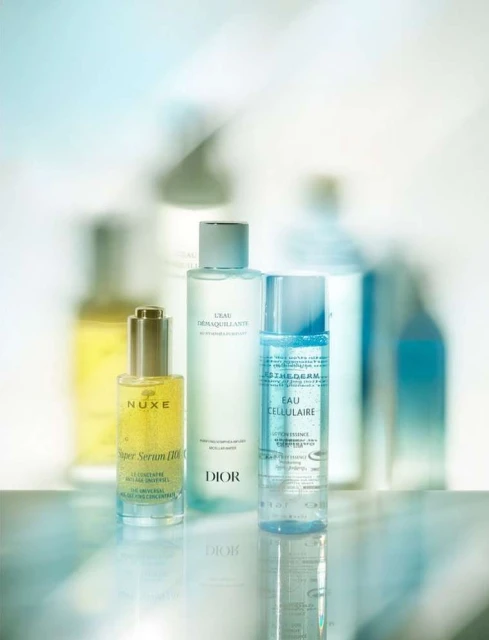 Several skincare products including serums and cleansers are arranged against a bright, diffused background, showcasing their packaging and textures.