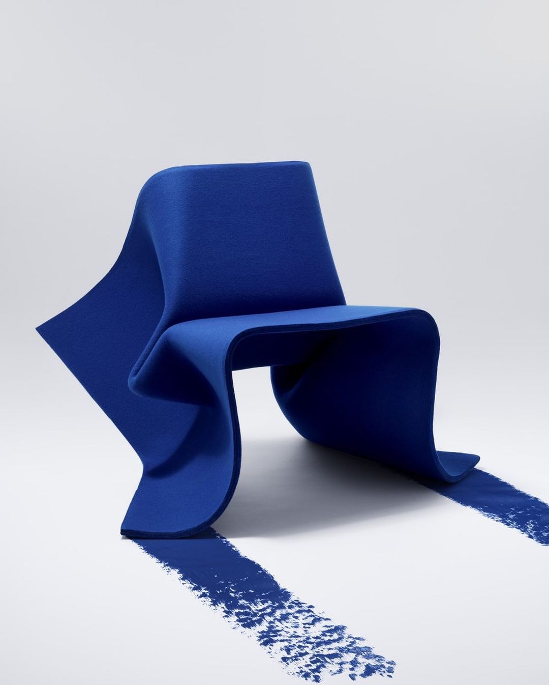 Modern royal blue chair on a white surface with a shadow, studio shot for interior design and furniture concepts.