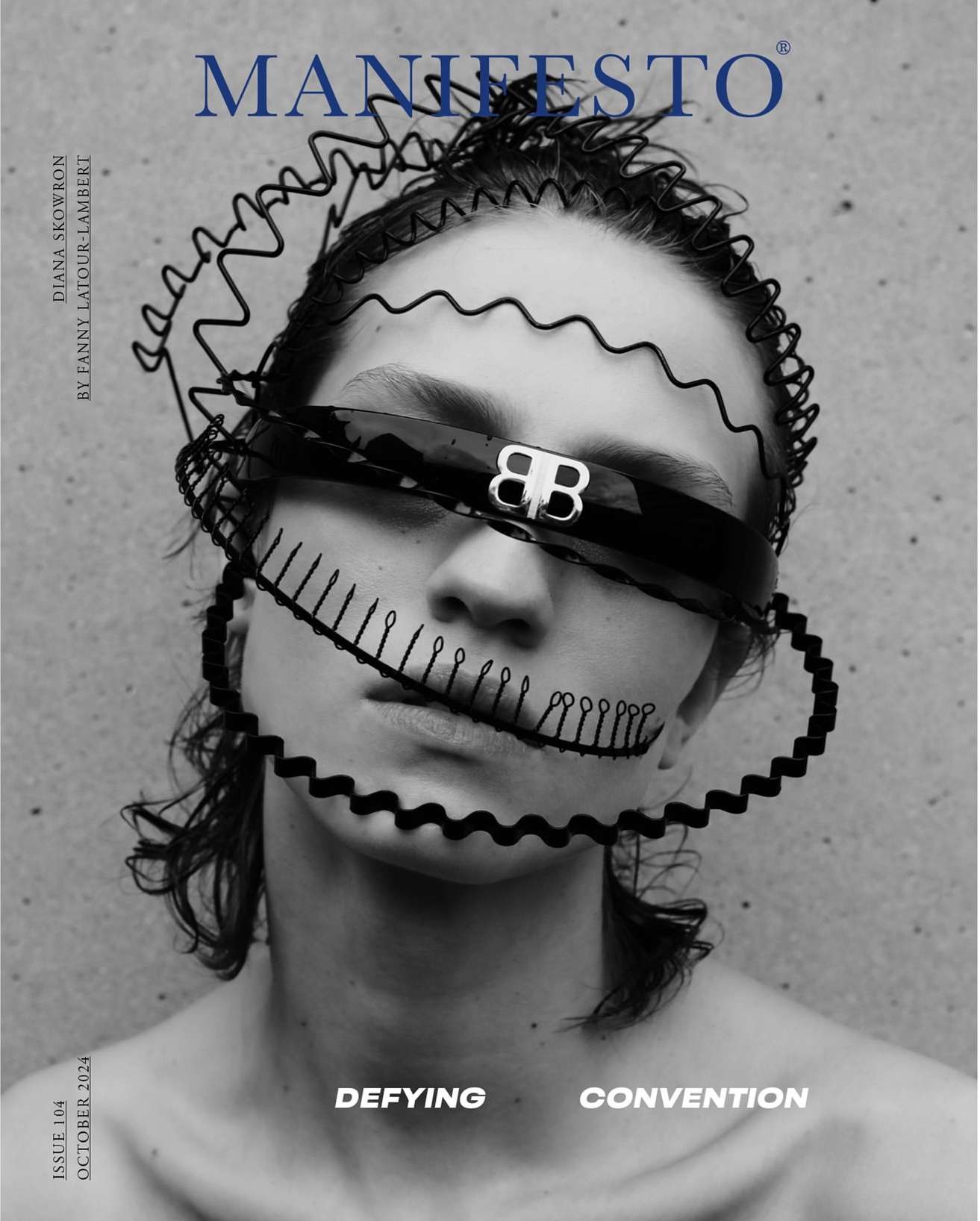 Black-and-white portrait of a woman with sculptural black adornments around her face, wearing a visor-like accessory, in a magazine cover.