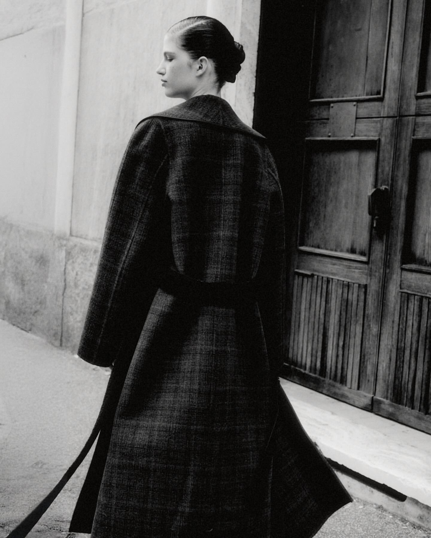 Monochrome fashion shot of a woman in an elegant wool coat, showcasing classic design and sophisticated style against an urban backdrop.