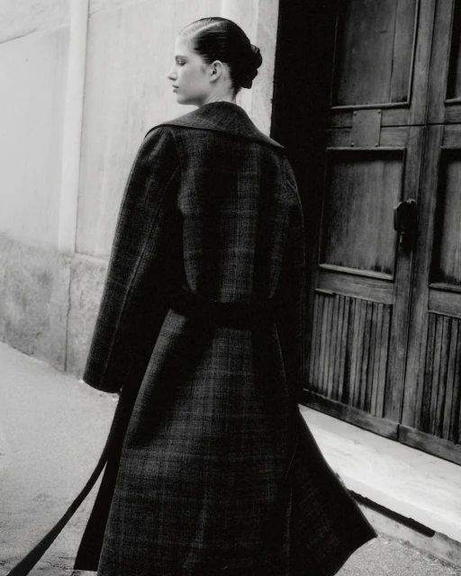 Monochrome fashion shot of a woman in an elegant wool coat, showcasing classic design and sophisticated style against an urban backdrop.