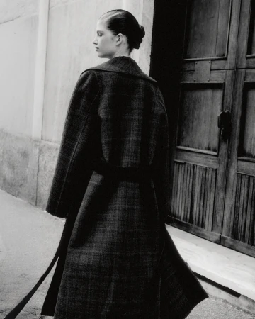 Monochrome fashion shot of a woman in an elegant wool coat, showcasing classic design and sophisticated style against an urban backdrop.