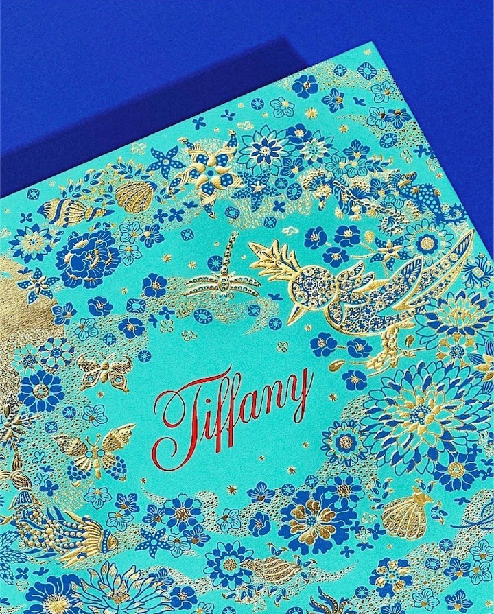 A visually appealing product shot featuring a teal box adorned with a blue and gold floral pattern and the name Tiffany in red script.