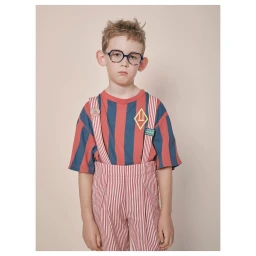 Young child wearing striped t-shirt, matching striped overalls, and dark blue glasses against a neutral background.