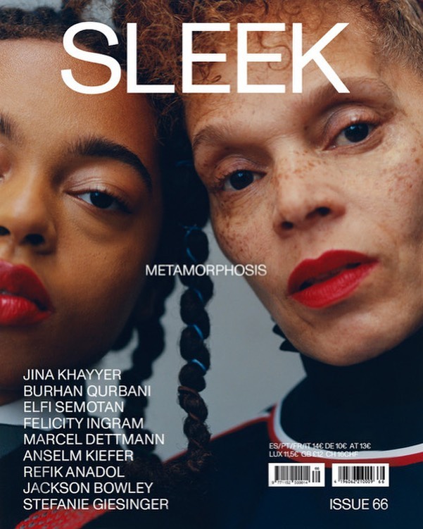 Close-up portrait of two female models with vibrant red lipstick and textured hairstyles against a plain background