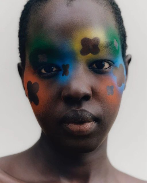 Striking portrait of an African woman with dark skin, adorned with vibrant face paint in shades of blue, green, yellow, and orange.