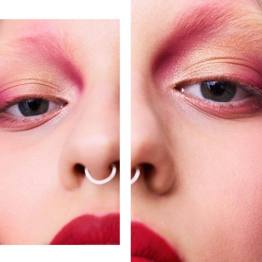 Extreme close-up of a model's face with creative makeup. Eyes are visible, with red lipstick and a nose ring. Beauty, fashion and editorial.