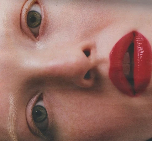 Close-up beauty portrait focusing on green eyes, fair skin with freckles, and glossy red lipstick by photographer Felicity Ingram