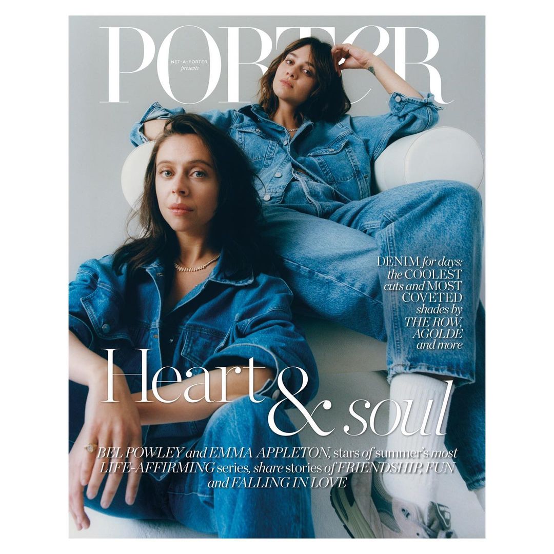 Two adult females in denim jackets and jeans sit in a photo studio for the cover of Porter magazine. Studio lighting is used.