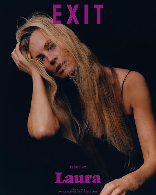 Portrait of a blonde woman with long hair holding her hand to her head against a dark background, photographed by Felicity Ingram.